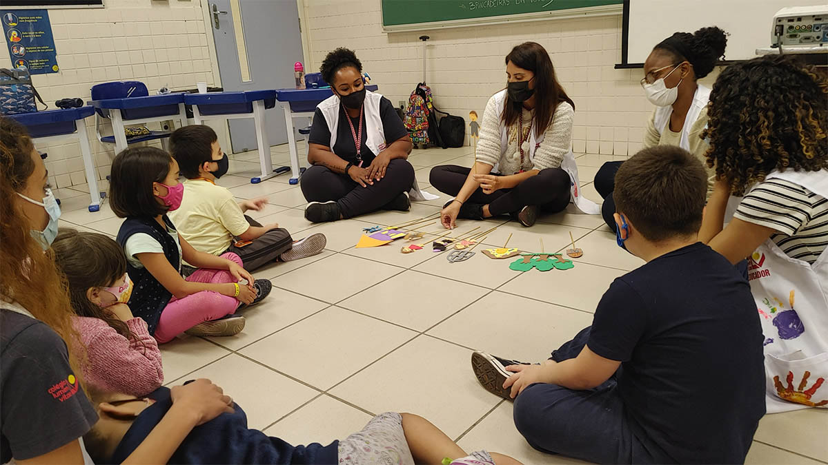 Imagem de alunos e equipe pedagógica sentados em sala em atividades diversas