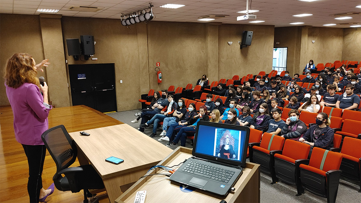 Foto de alunos em auditório assistindo a uma apresentação