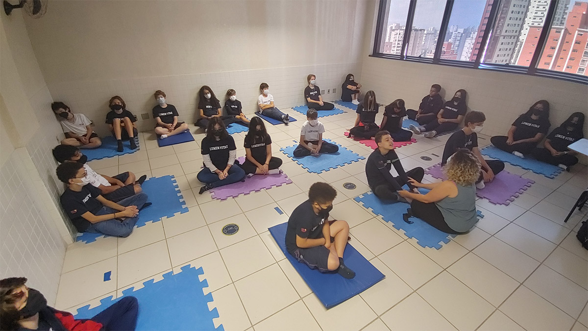 Foto de grupo de alunos sentados em tapetes de EVA