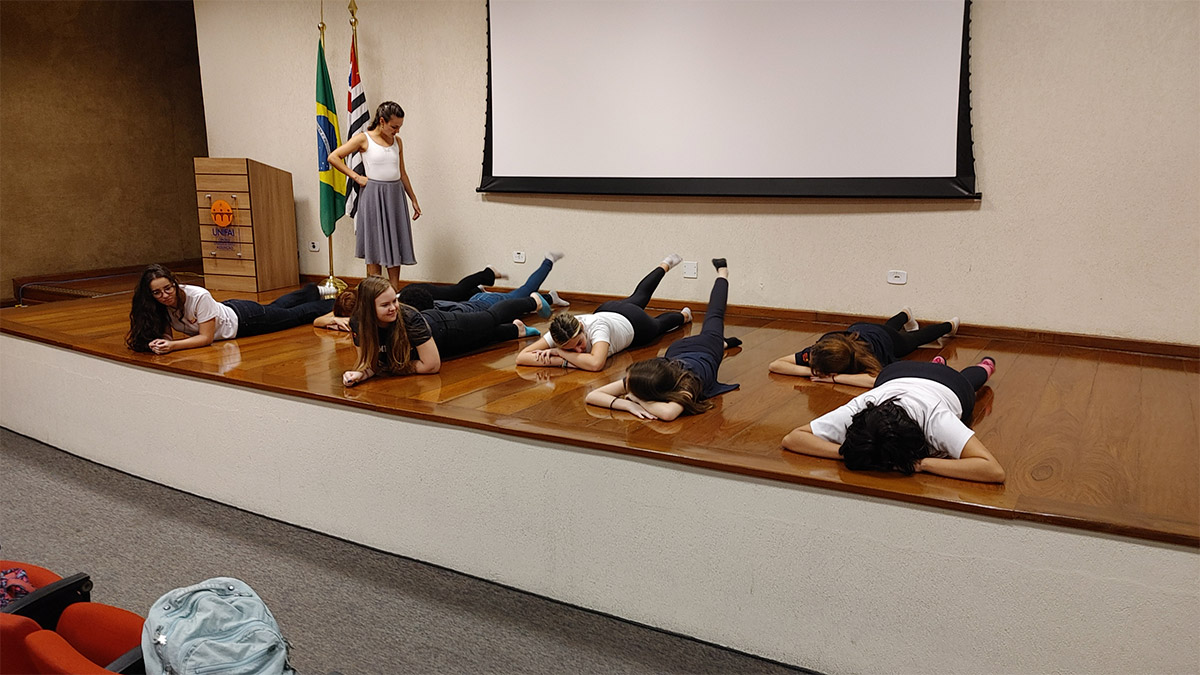 Foto de alunos deitados em palco