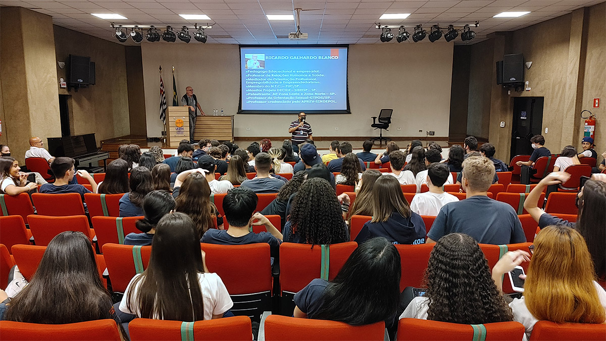 Foto de alunos em auditório assistindo a uma apresentação