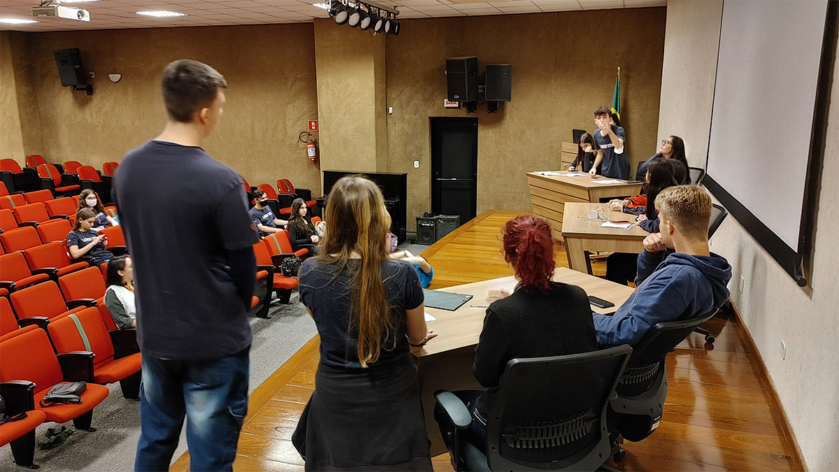 Foto de alunos reunidos em auditório que assistem a uma apreentação