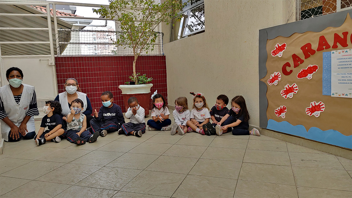 Foto de professoras e alunos sentados posando para foto